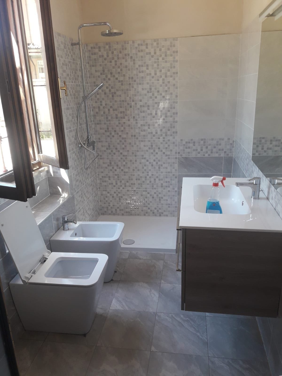 Bagno ristrutturato da VGA Impresa Edile con doccia rivestita a mosaico, mobile lavabo sospeso e sanitari sospesi