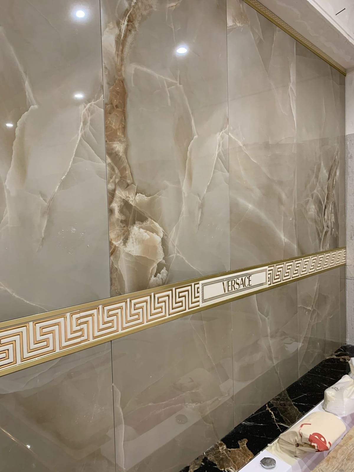 Parete rivestita con lastre effetto onice e greca decorativa dorata
