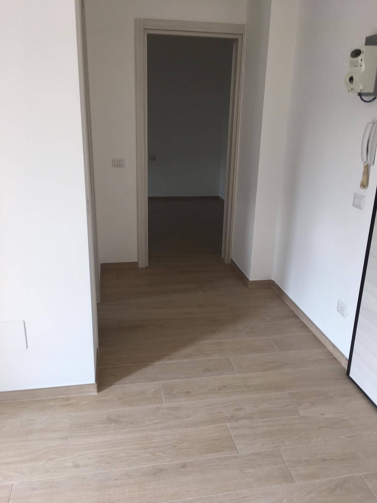 Corridoio appena tinteggiato di bianco con porte interne nuove e pavimento effetto legno